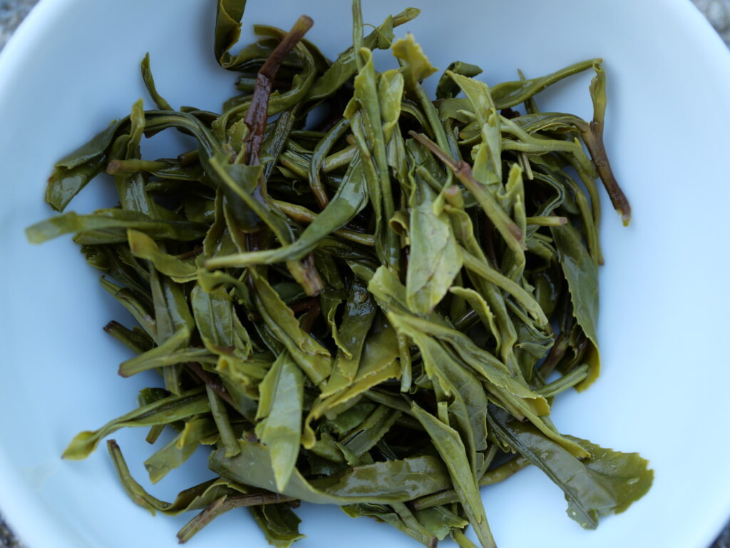 Steeped green tea leaves in a white bowl